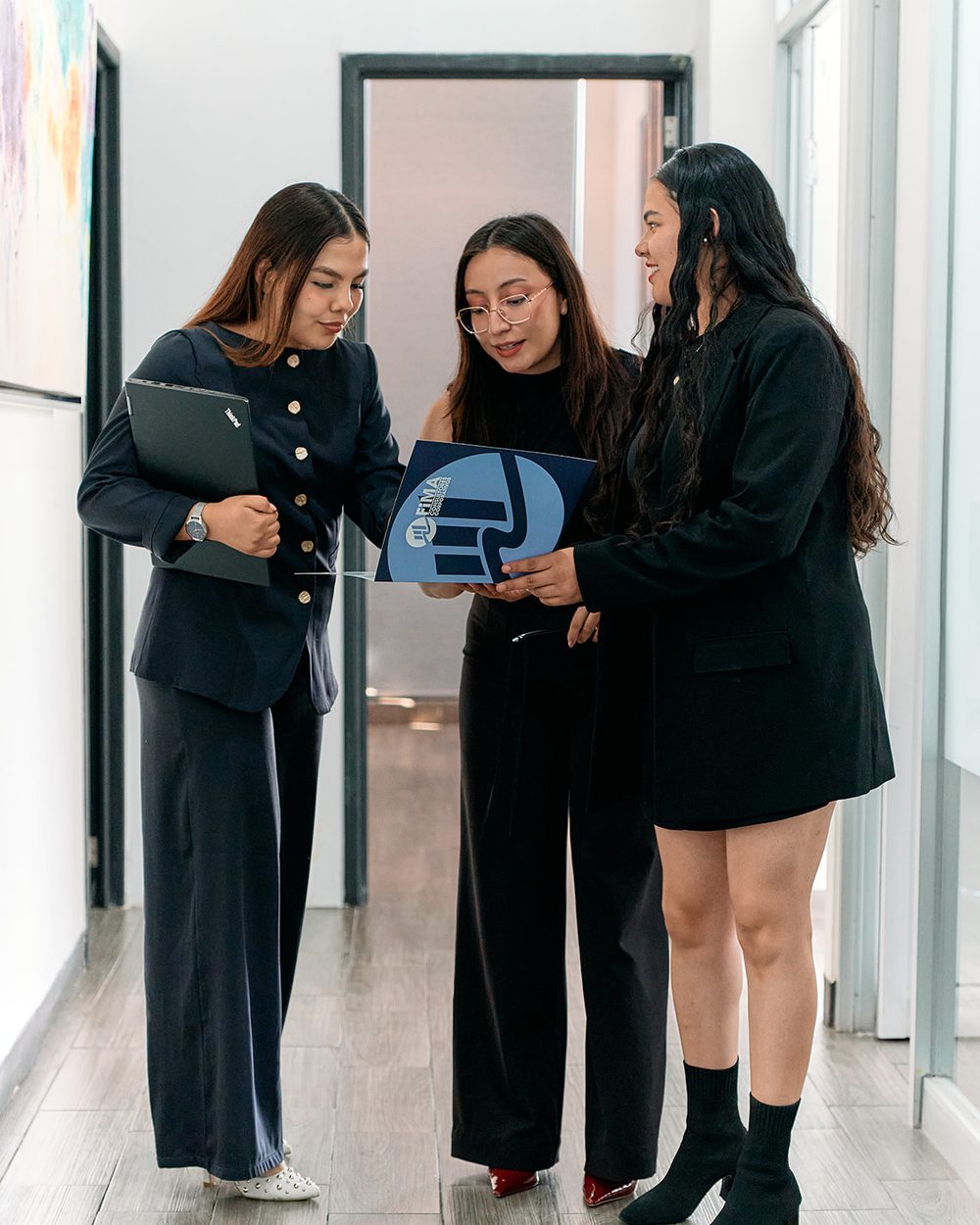 Tres integrantes del equipo de FIMA revisando un documento en las oficinas de la firma